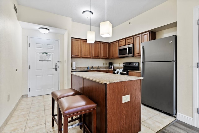 kitchen with light tile patterned flooring, stainless steel appliances, a sink, a kitchen island, and pendant lighting