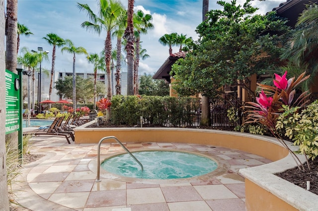 view of swimming pool featuring a community hot tub, a patio area, and fence