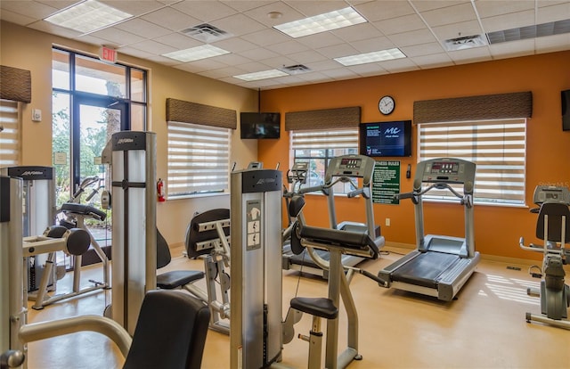 exercise room with baseboards, visible vents, and a drop ceiling