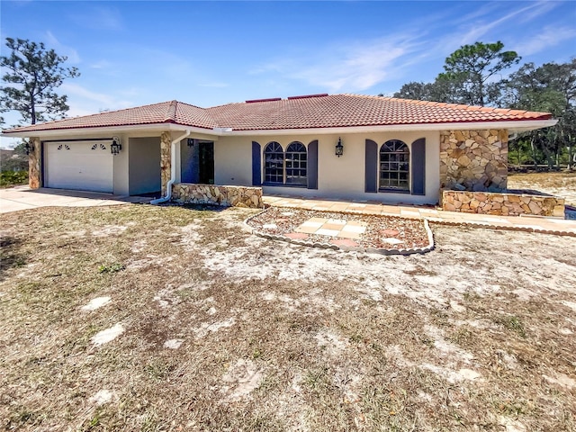 view of front of house with a tiled roof, stucco siding, driveway, stone siding, and an attached garage