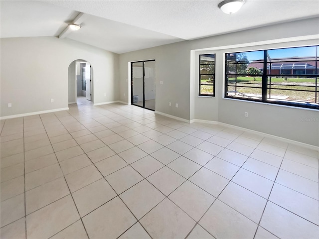 empty room featuring baseboards, arched walkways, and vaulted ceiling with beams