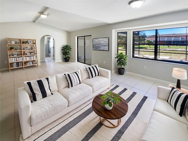 tiled living room featuring arched walkways, lofted ceiling with beams, and baseboards