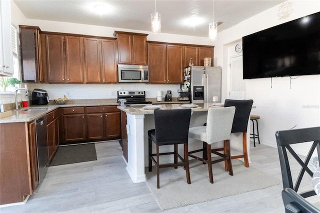 7407 Ripplepointe Way, Windermere, FL 34786 - kitchen featuring appliances with stainless steel finishes, a sink, a kitchen island, hanging light fixtures, and a breakfast bar area