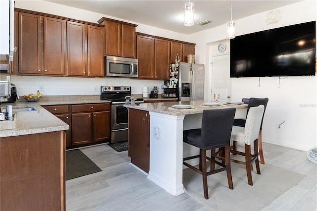 7407 Ripplepointe Way, Windermere, FL 34786 - kitchen featuring stainless steel appliances, light wood-style floors, tasteful backsplash, and a kitchen island