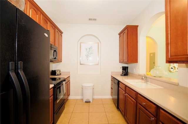 kitchen with light tile patterned floors, a sink, visible vents, light countertops, and black appliances