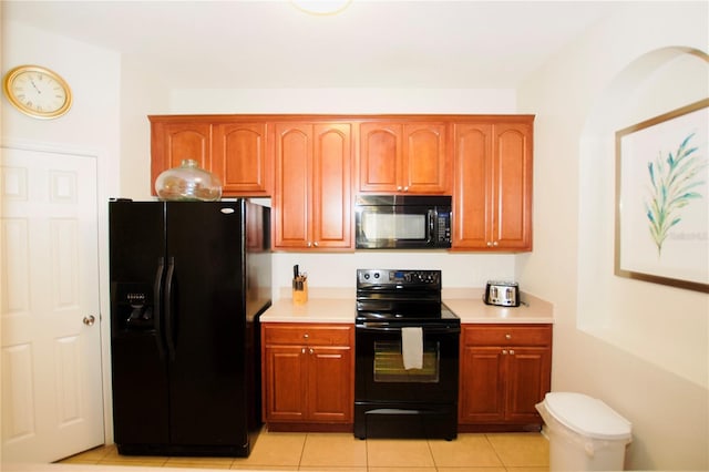 kitchen featuring light tile patterned floors, black appliances, light countertops, and brown cabinets