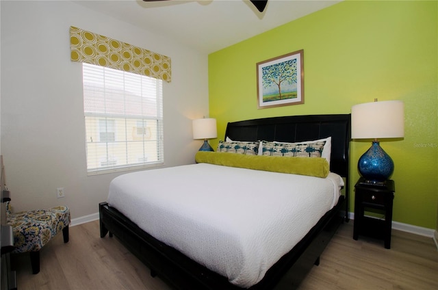 bedroom with ceiling fan, wood finished floors, and baseboards