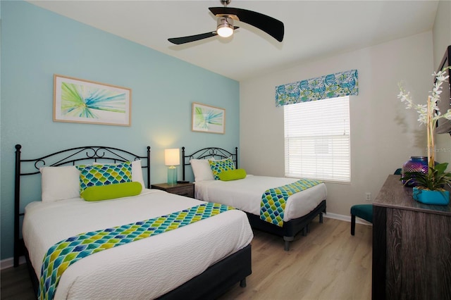 bedroom featuring a ceiling fan, light wood-style flooring, and baseboards