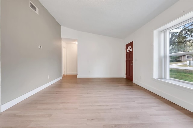 spare room with light wood-type flooring, visible vents, and baseboards