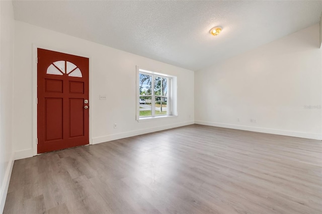 entrance foyer featuring a textured ceiling, baseboards, and wood finished floors