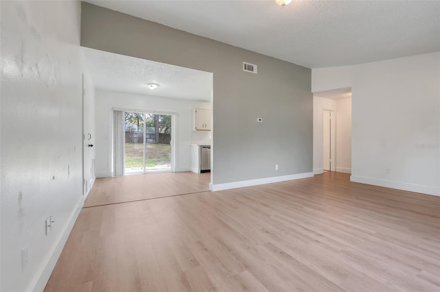 unfurnished living room featuring light wood-style floors, baseboards, visible vents, and a textured ceiling