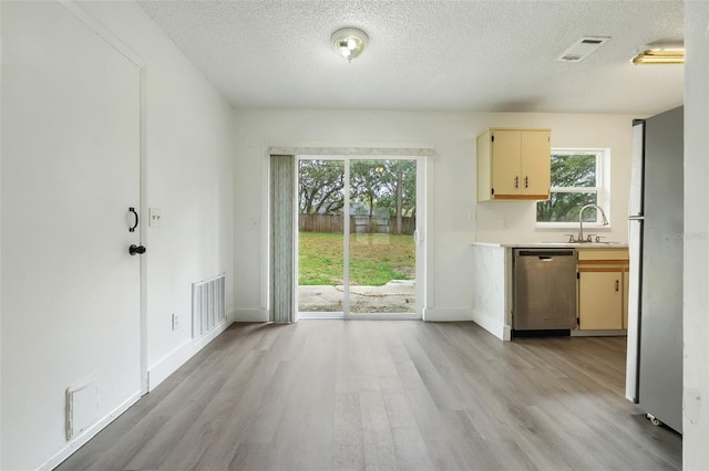 kitchen featuring a sink, visible vents, light countertops, light wood-type flooring, and dishwasher