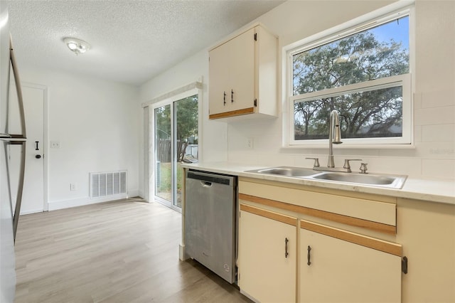 kitchen with visible vents, dishwasher, light countertops, light wood-style floors, and a sink