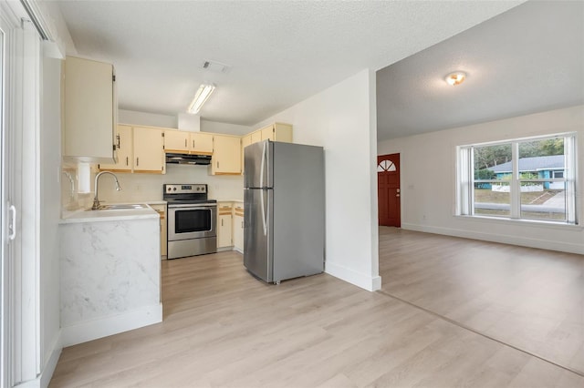 kitchen featuring cream cabinets, stainless steel appliances, light countertops, under cabinet range hood, and a sink