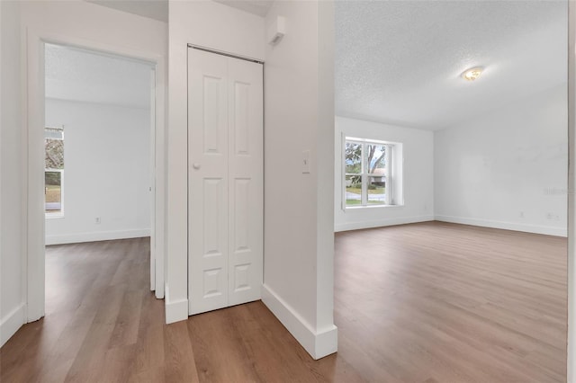 interior space with baseboards, a textured ceiling, and wood finished floors