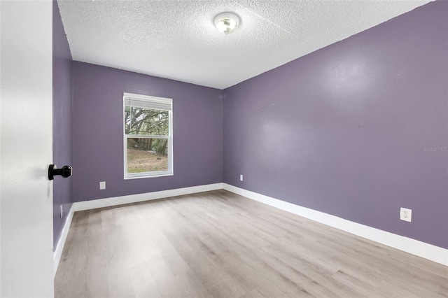 empty room with a textured ceiling, baseboards, and wood finished floors