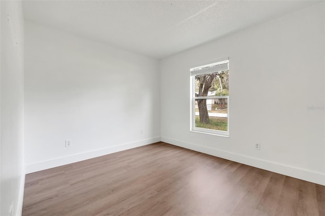 spare room with a textured ceiling, baseboards, and wood finished floors