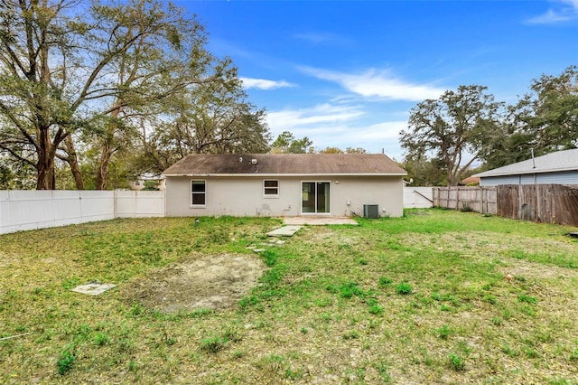 rear view of house featuring a yard, central AC, a fenced backyard, and stucco siding