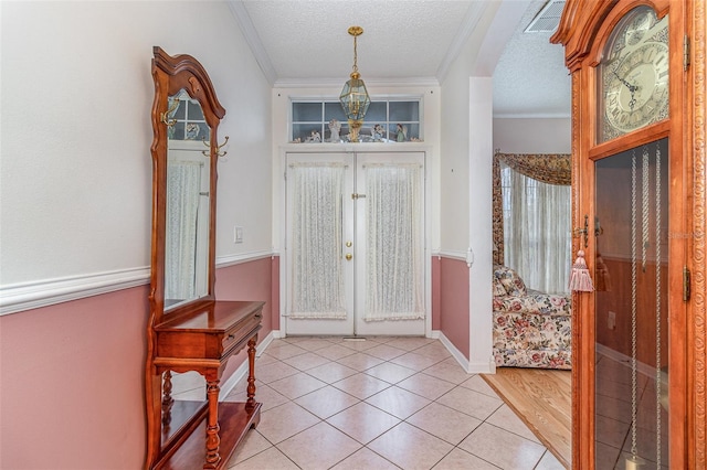 foyer with visible vents, crown molding, french doors, light tile patterned flooring, and a textured ceiling