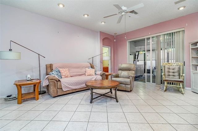 living room with ceiling fan, light tile patterned floors, arched walkways, and a textured ceiling