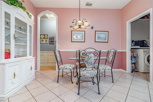 dining room featuring visible vents, light tile patterned floors, wainscoting, arched walkways, and washer / clothes dryer