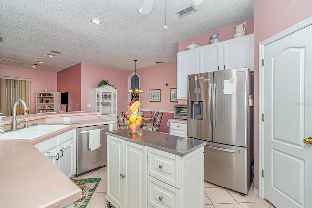 kitchen with visible vents, light tile patterned flooring, a sink, stainless steel appliances, and white cabinetry