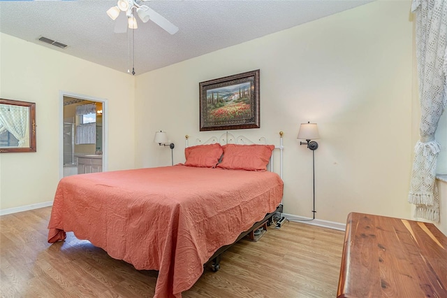 bedroom featuring visible vents, connected bathroom, baseboards, wood finished floors, and a textured ceiling