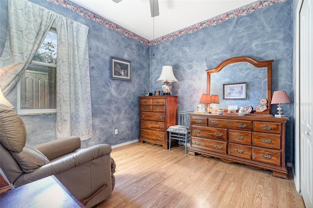 sitting room featuring ceiling fan, baseboards, wood finished floors, and wallpapered walls