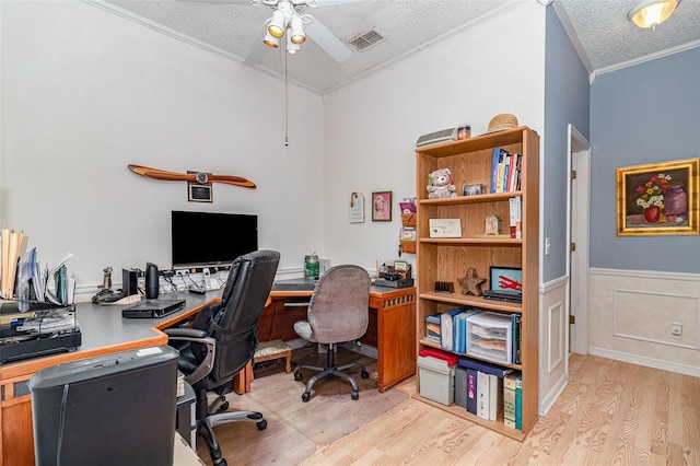 home office featuring visible vents, a wainscoted wall, a textured ceiling, wood finished floors, and crown molding