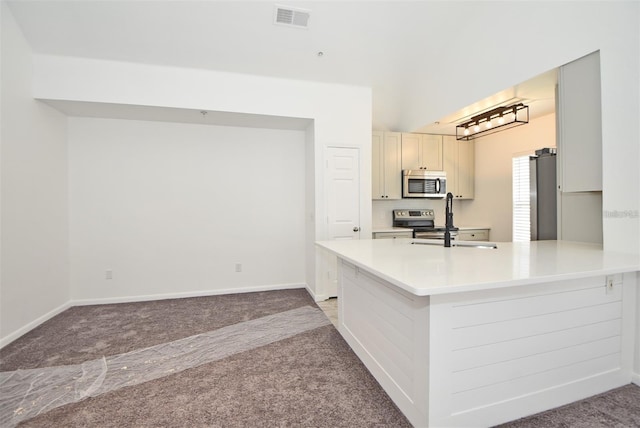 kitchen with light carpet, a sink, visible vents, light countertops, and appliances with stainless steel finishes