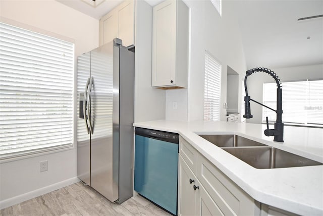 kitchen featuring dishwashing machine, a sink, baseboards, stainless steel fridge with ice dispenser, and light wood finished floors