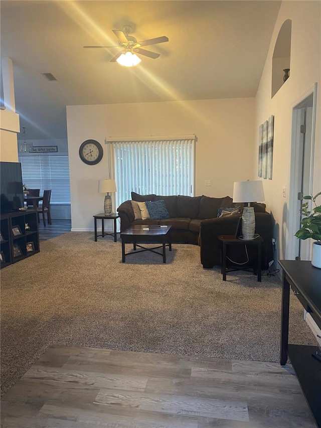 living area with visible vents, wood finished floors, a ceiling fan, and vaulted ceiling