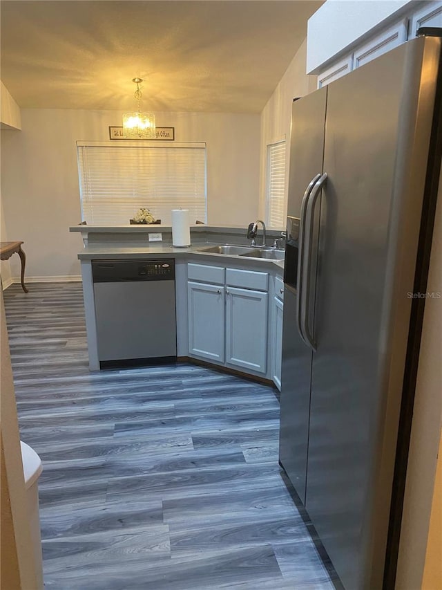 kitchen featuring a sink, dark countertops, dark wood-style floors, appliances with stainless steel finishes, and a chandelier