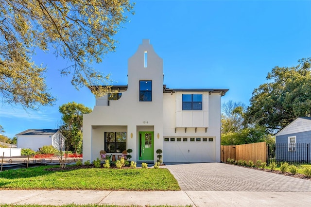 view of front of house featuring a front yard, fence, an attached garage, stucco siding, and decorative driveway