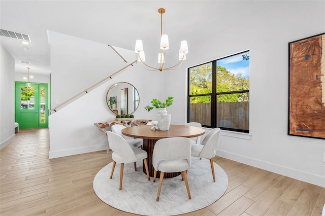 dining space with a chandelier, visible vents, baseboards, and light wood-style floors