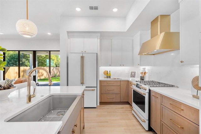 kitchen featuring visible vents, light countertops, white appliances, wall chimney exhaust hood, and a sink