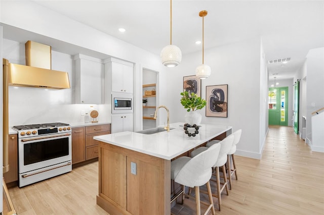 kitchen featuring visible vents, a sink, stainless steel microwave, wall chimney exhaust hood, and white gas range