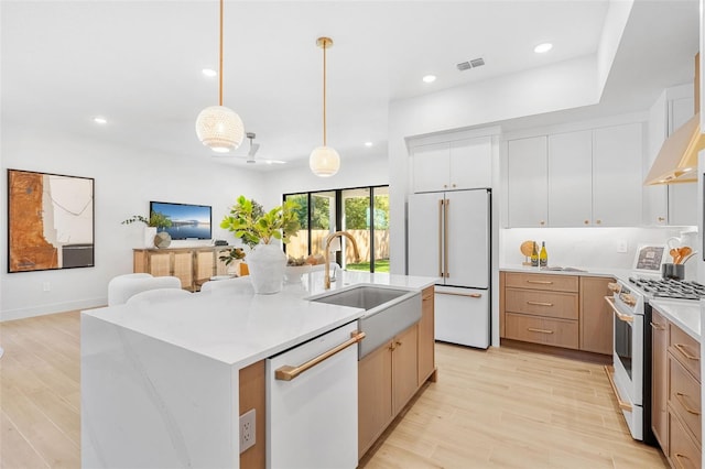 kitchen with visible vents, decorative light fixtures, light wood-type flooring, white appliances, and a sink