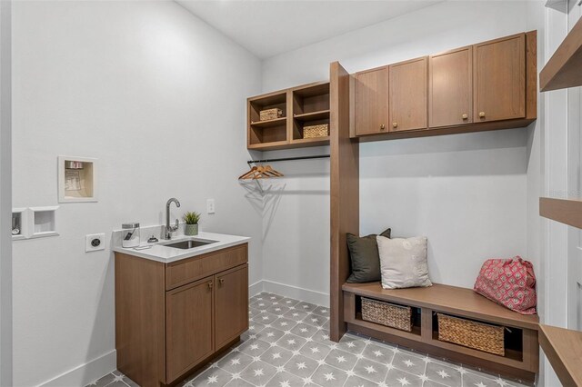 laundry room with baseboards, washer hookup, cabinet space, electric dryer hookup, and a sink