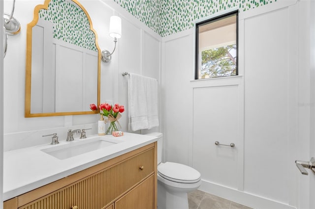 half bathroom featuring tile patterned flooring, toilet, and vanity