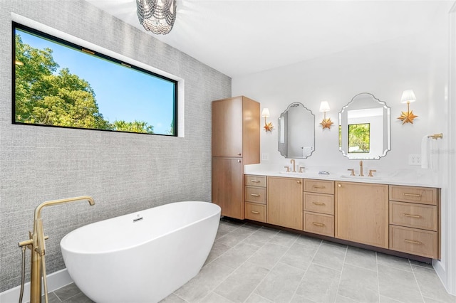 full bathroom with double vanity, a freestanding bath, and a sink