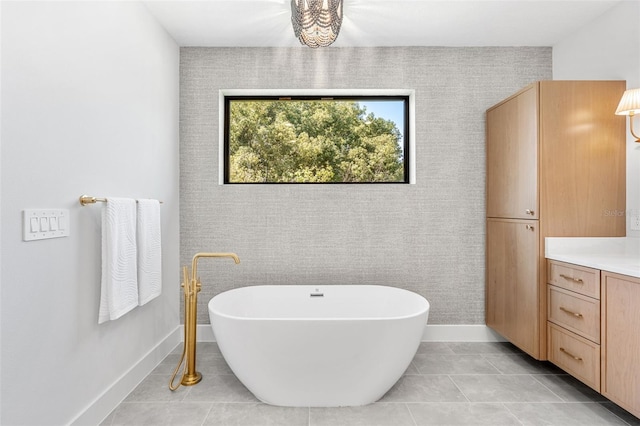 bathroom featuring a freestanding tub, baseboards, vanity, and tile patterned flooring