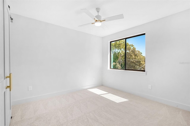 carpeted spare room featuring baseboards and ceiling fan