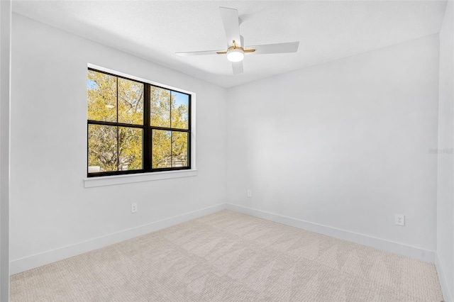 carpeted empty room featuring ceiling fan and baseboards