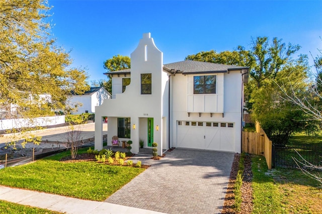 view of front of property featuring decorative driveway, fence, an attached garage, and stucco siding