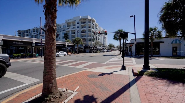 view of road with street lights, curbs, sidewalks, and traffic lights