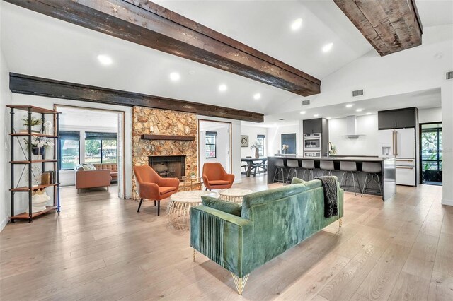 living area with visible vents, lofted ceiling with beams, recessed lighting, light wood-style flooring, and a fireplace