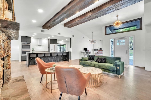 living area with visible vents, beam ceiling, a notable chandelier, light wood finished floors, and baseboards