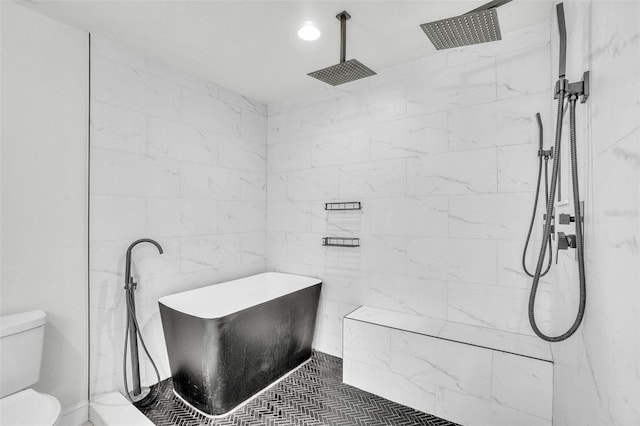 bathroom featuring a tile shower, a freestanding bath, toilet, and tile walls