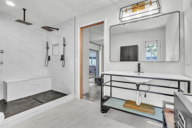 bathroom featuring marble finish floor, vanity, and a tile shower